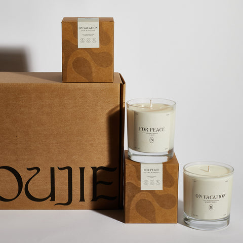Boujie On Vacation and For Peace scented soy jar candles displayed with eco-friendly packaging. Boujie On Vacation and For Peace scented soy jar candles displayed with eco-friendly packaging.