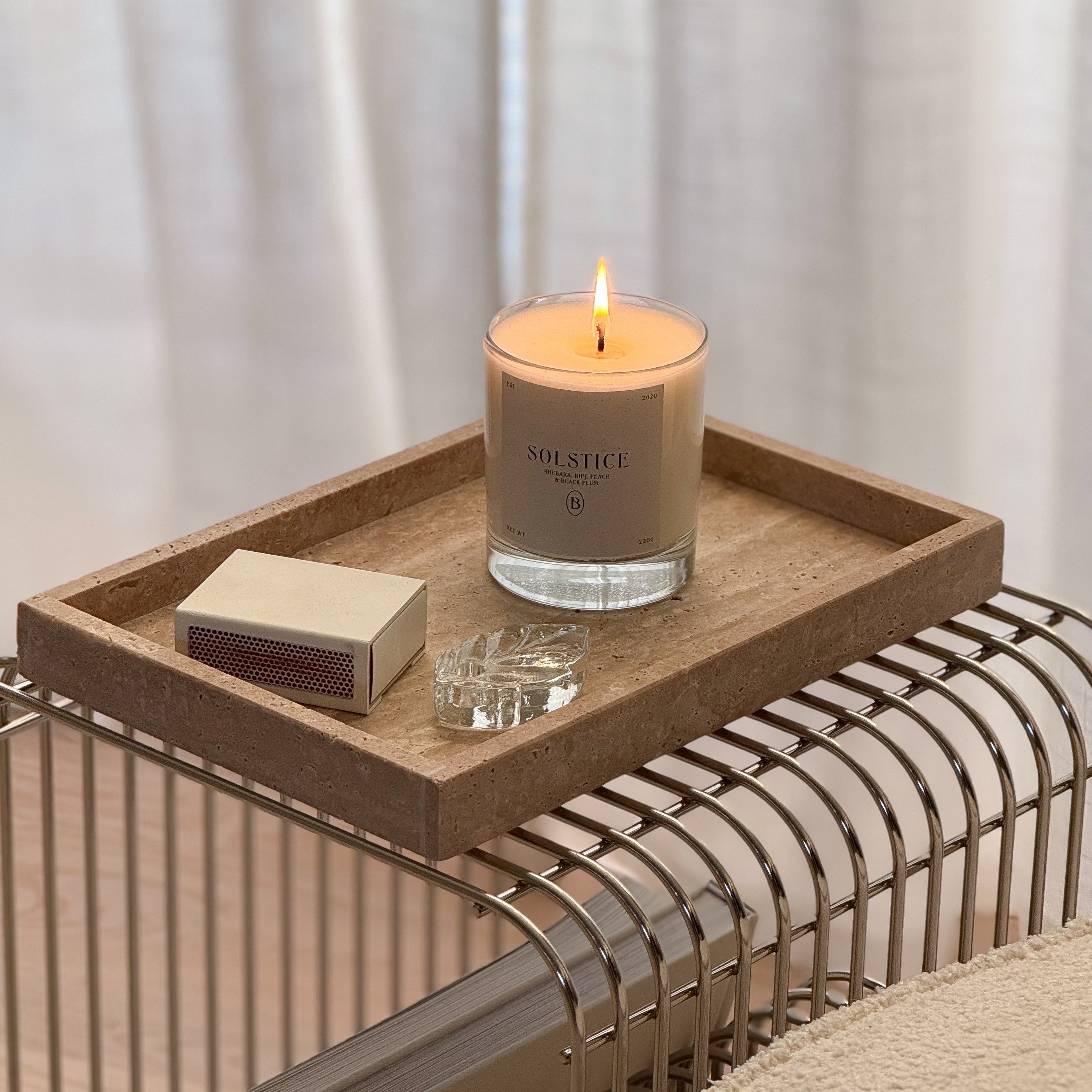 Boujie Solstice candle glowing softly on stone tray with matches and crystal accent, highlighting minimalist luxury home style. Boujie Solstice candle glowing softly on stone tray with matches and crystal accent, highlighting minimalist luxury home style.