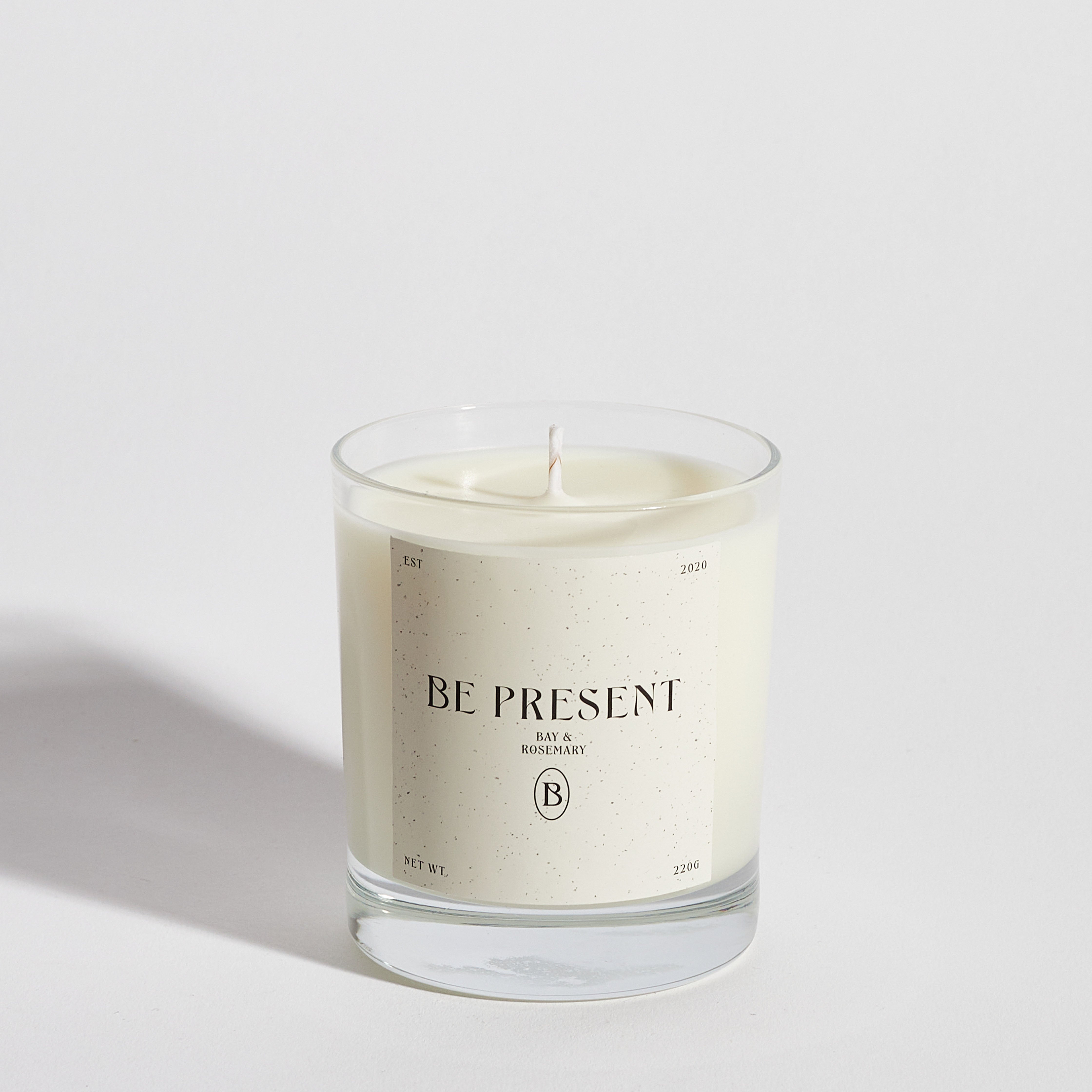 Boujie Be Present luxury soy wax jar candle, front view, handmade with natural soy wax in a clear glass jar, scented with bay and rosemary, surrounded by dried bay leaves, rosemary sprig, and lemon slice.