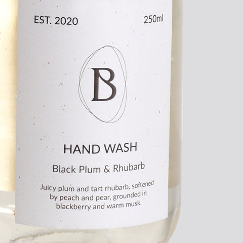 Hand wash bottle with label featuring 'Black Plum & Rhubarb' fragrance on a white background
