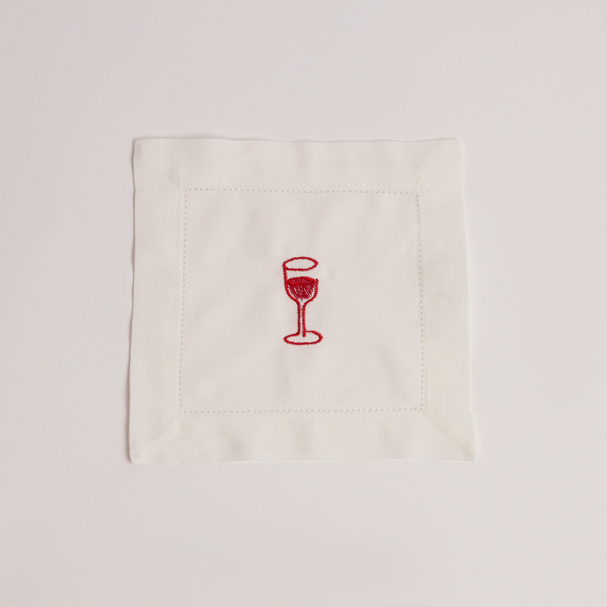 Single white cocktail napkin embroidered with a red wine glass.