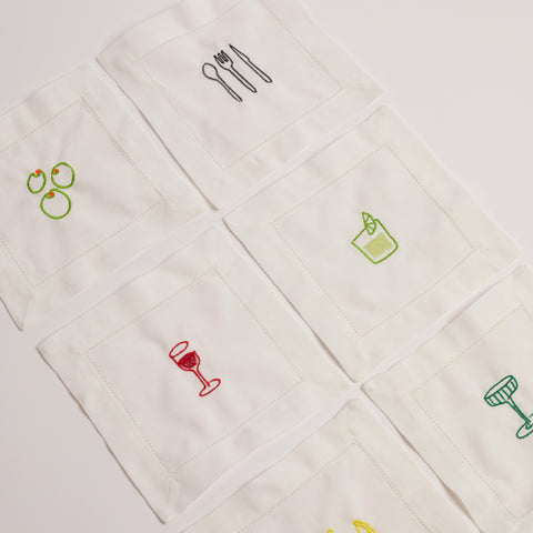 Full set of embroidered cocktail napkins laid flat, showing six colourful drink and food motifs.