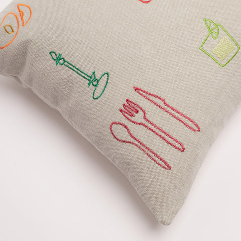 Close-up detail of red cutlery embroidery on neutral linen cushion.