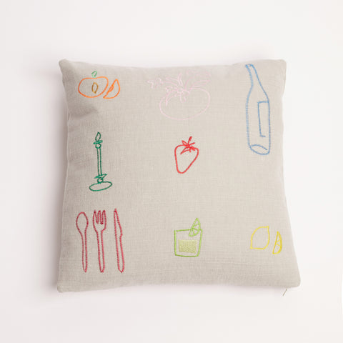 Neutral linen cushion with colourful embroidered food and drink icons on a white background.