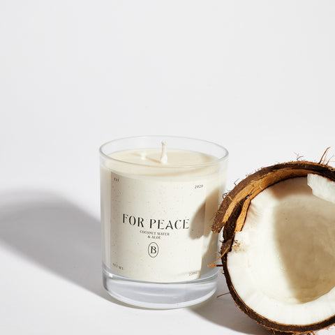 Boujie For Peace scented jar candle with half a fresh coconut, highlighting its tropical spa-like aroma of coconut water and aloe.