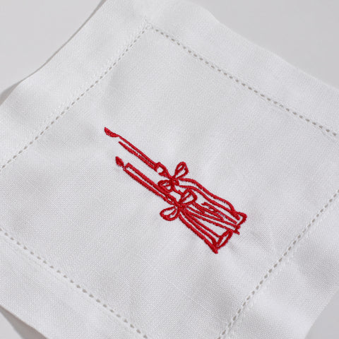 White fabric with red embroidered design of a broom and wreath on a white background