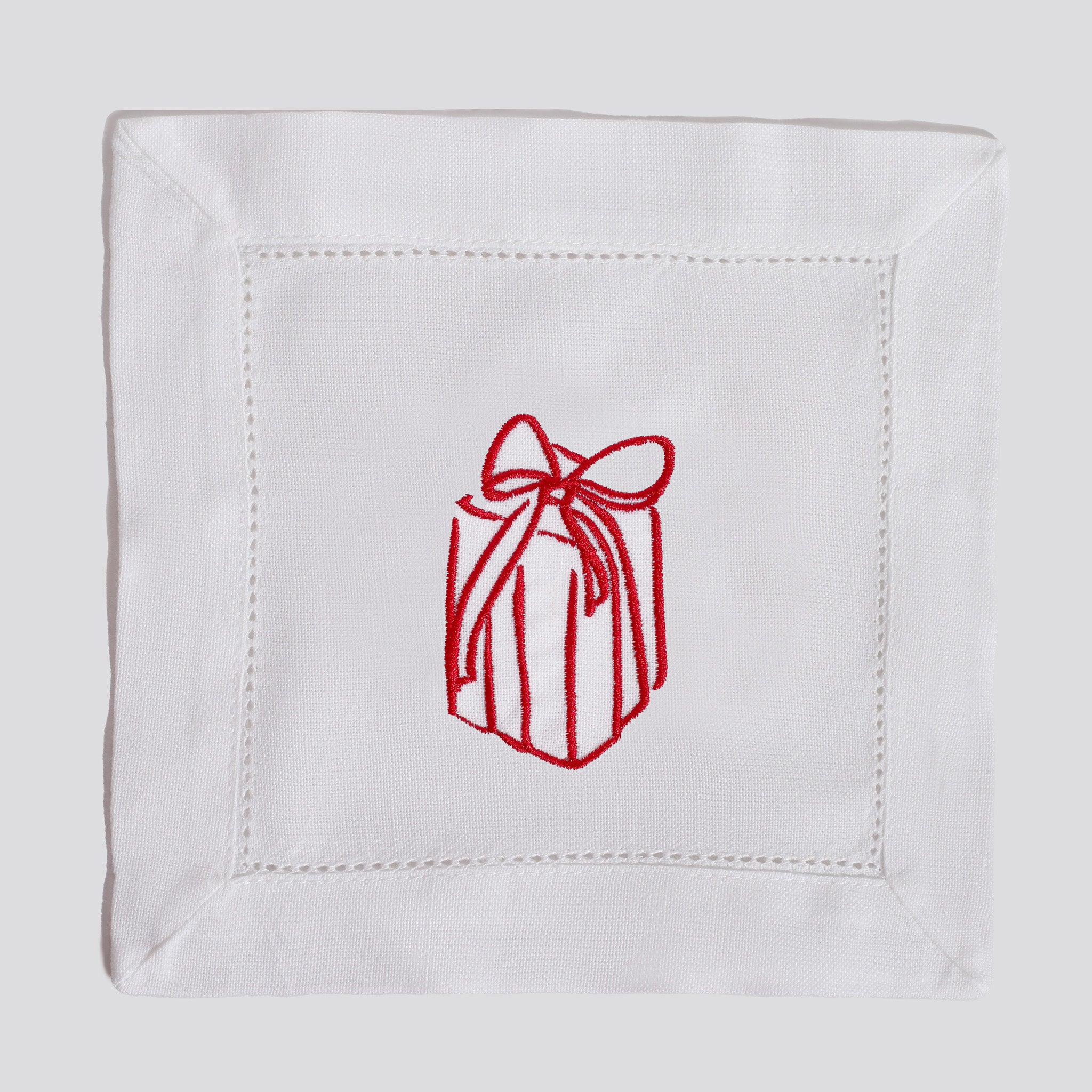 White napkin with red embroidered gift box design on a white background