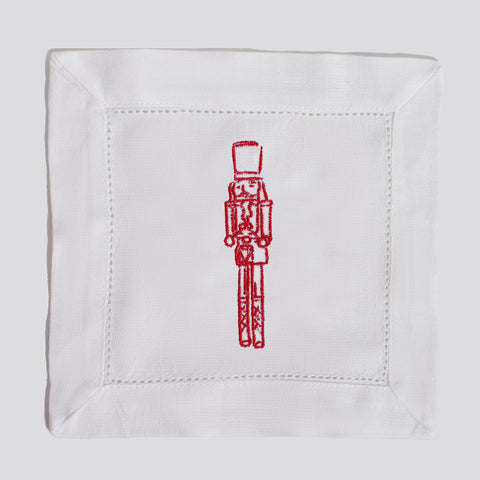 White napkin with red embroidered nutcracker design on a white background