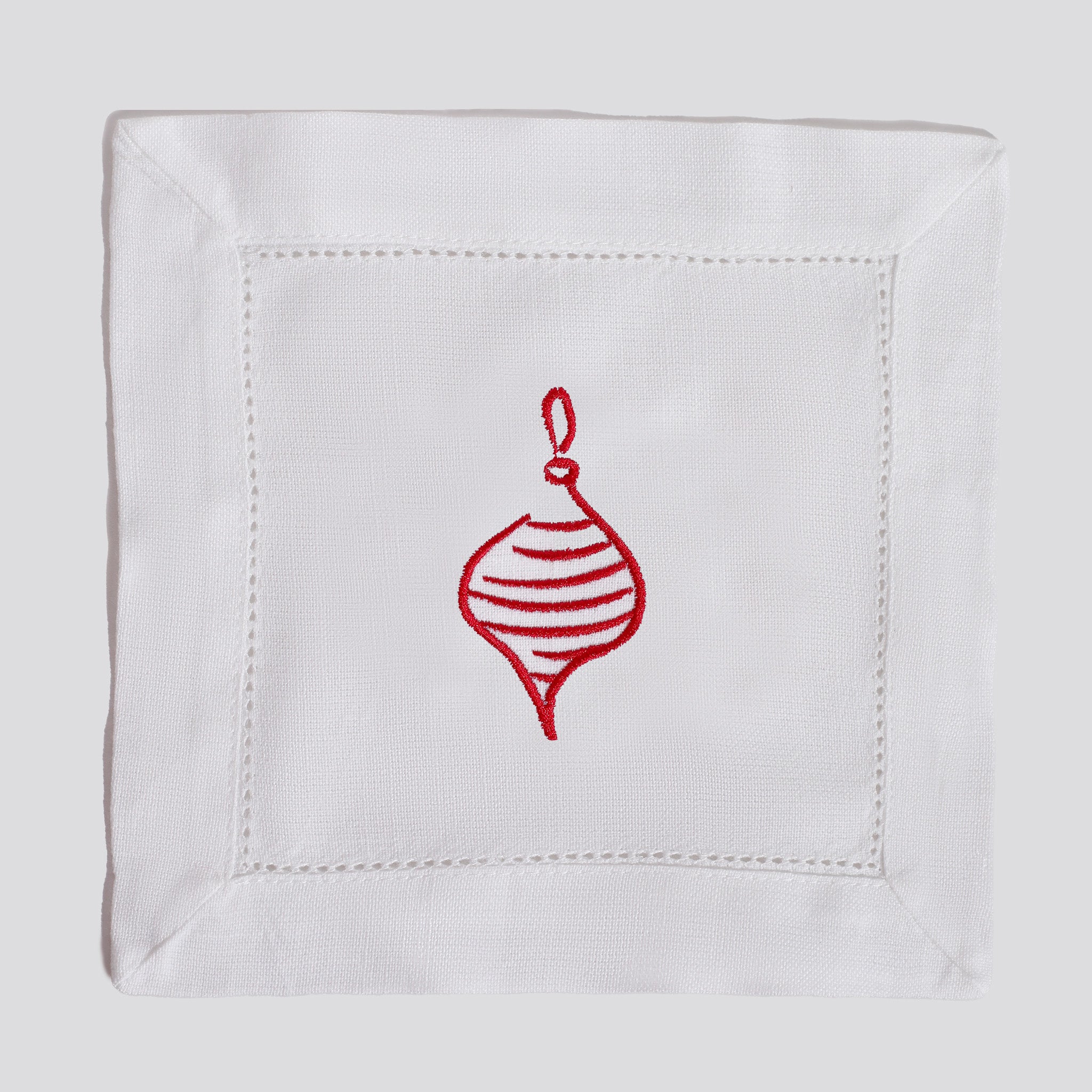 White napkin with a red embroidered Christmas ornament on a white background