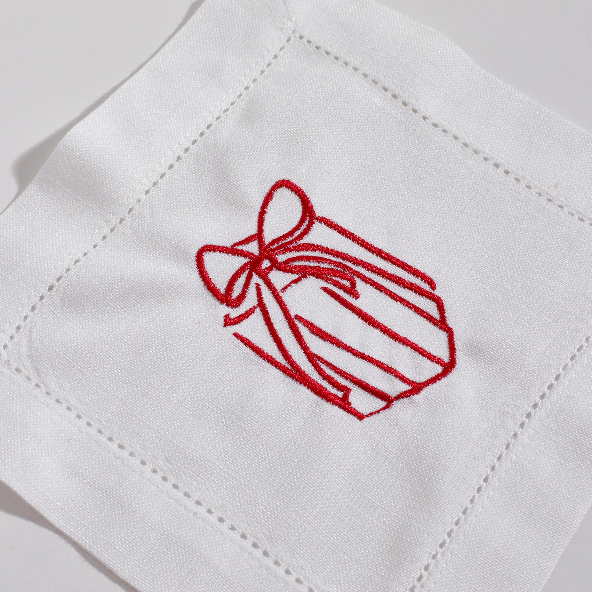 White fabric with red embroidered bow design on a white background