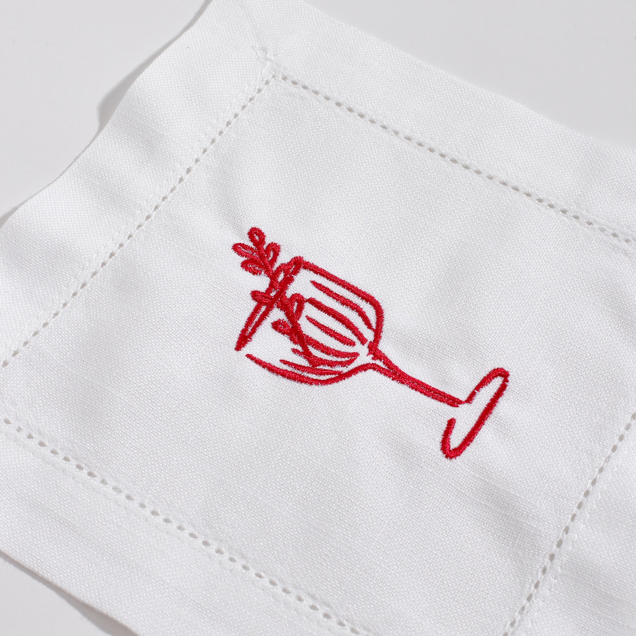 Red embroidered wine glass design on a white fabric background