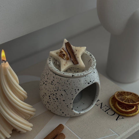 Star-shaped soy wax melt decoration on a ceramic burner, festive display.